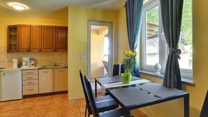 Cocina compacta con armarios de madera, un refrigerador pequeño y un comedor con mesa y sillas.