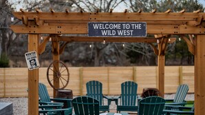 A wooden pergola with a sign reading "WELCOME TO THE WILD WEST" and a wanted poster. - 5BR Oasis w Pool, Spa & Fire Pit (Round Rock)
