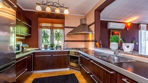 Een moderne keuken met donkerhouten kasten, roestvrijstalen apparatuur, een zwart vloerkleed en een raam met planten.