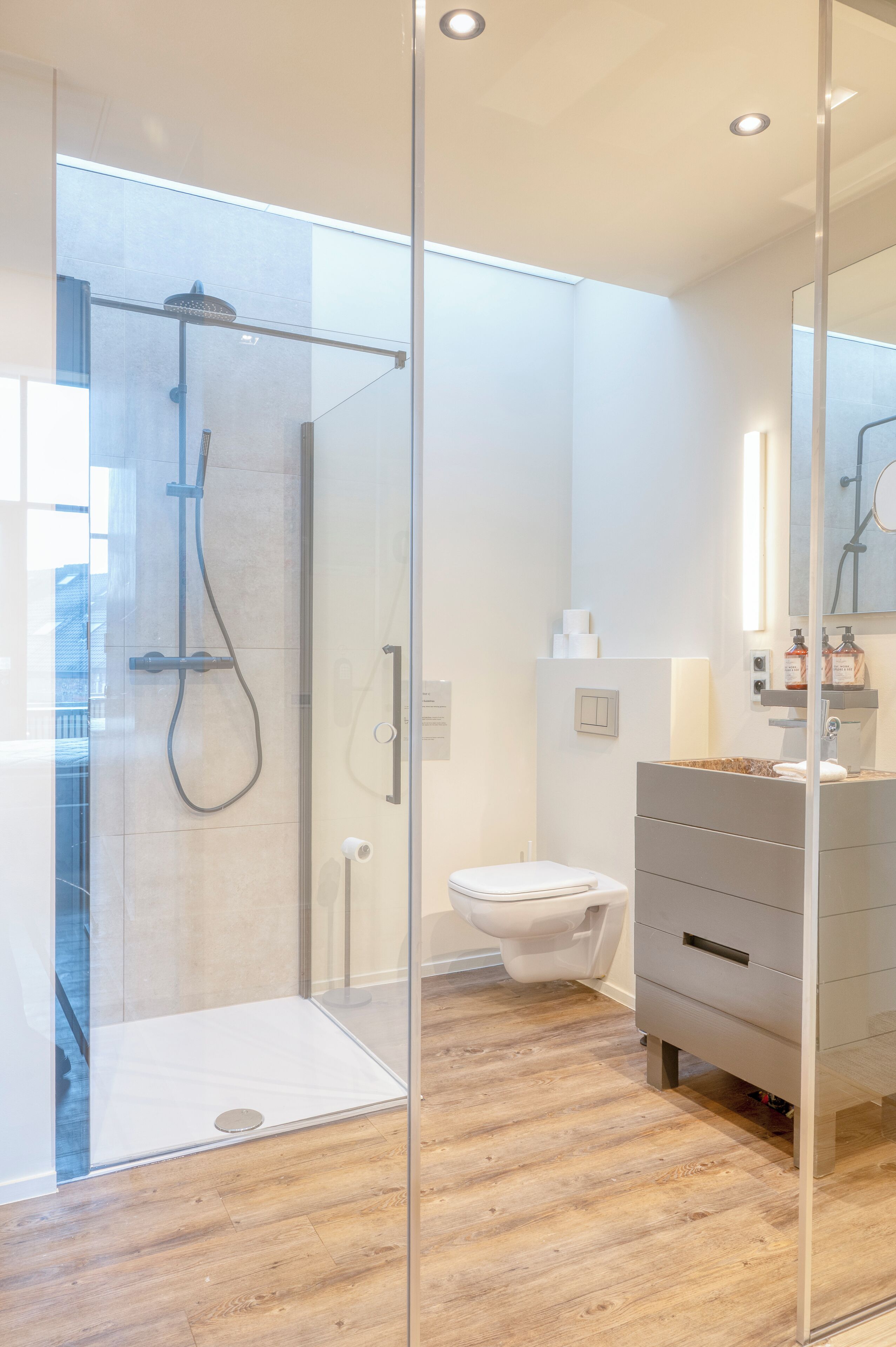 Een moderne badkamer met een douchecabine van glas, een toilet en een wastafel met spiegel.