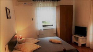 A bedroom with a bed, bedside lamp, and a television on a stand. - Apartments Winny (73623-A1) - Banjole (Banjole)