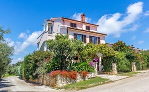 A two-story house with a stone facade, a balcony, and a garden with various plants and flowers. - Apartments Winny (73623-A1) - Banjole (Banjole)
