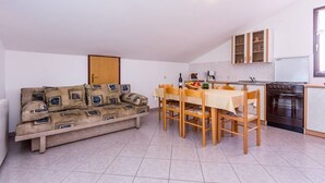Ett kompakt bostadsutrymme med en soffa, ett matbord, stolar, ett köksområde med en spis och skåp.