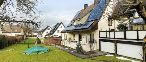 A residential area with houses, a green lawn, and solar panels on one house.