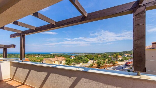 Ein Balkon mit Blick auf eine Küstenstadt, Holzträger und ein Fliesenboden.