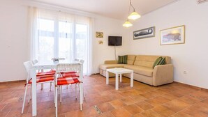 Ein Wohnzimmer mit einer Couch, einem Couchtisch, einem Fernseher und einem Esstisch mit Stühlen.