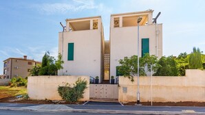 Ein modernes Gebäude mit einer symmetrischen Fassade, bestehend aus zwei Hauptbereichen mit grünen Fensterläden und einem zentralen Eingang.