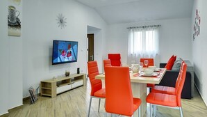 Ett modernt matområde med ett träbord, röda stolar och en tv som är monterad på väggen.