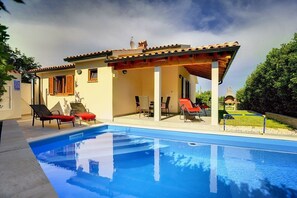 A poolside area with a clear blue pool, lounge chairs, and a covered patio. - House Mareti (73652-K1) - Liznjan (Liznjan)