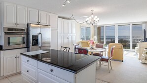 A modern kitchen with a central island, built-in appliances, and a dining area with a view. - Smuggler's Cove 205, 2BR 2BA Oceanfront Condo in Atlantic Beach! (Atlantic Beach)