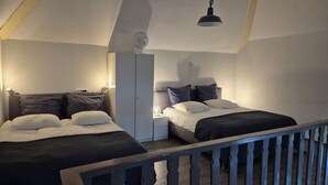 Ein Schlafzimmer mit zwei Betten, einem Kleiderschrank, einem Schreibtisch und einer Deckenleuchte.