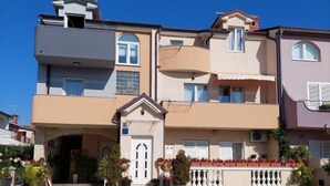 Un edificio residenziale a più piani con un ingresso centrale, balconi e piante in vaso.