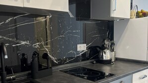 A modern kitchen with white cabinets, a black countertop, and a built-in oven. - Apartments Vuletic (73661-A3) - Medulin (Medulin)