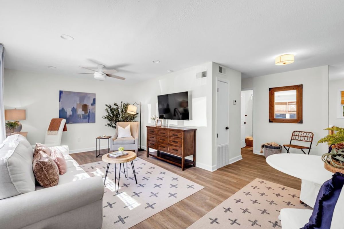 A modern living room with a sofa, coffee table, TV, and a dining area with a table and chairs.
