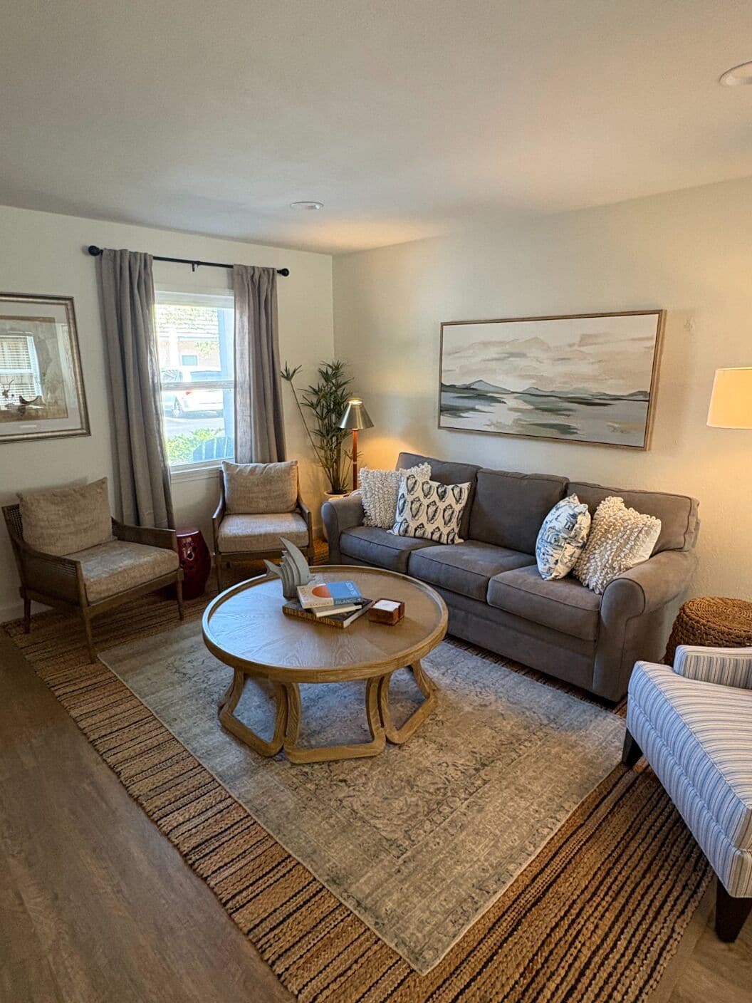 A living room with a sofa, armchairs, a coffee table, and a rug.