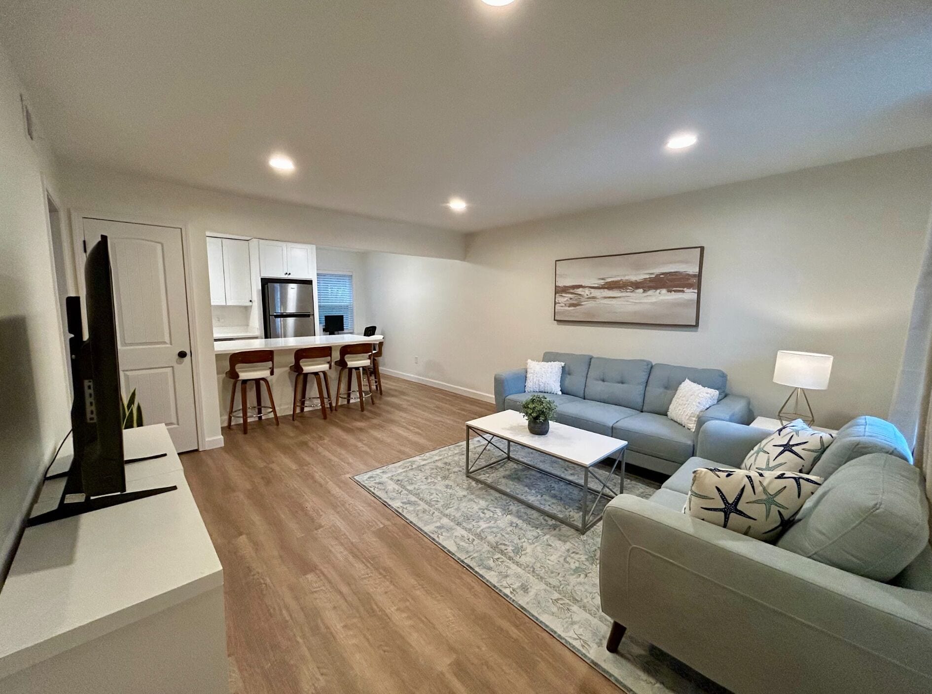 A modern living room with a grey sofa, a coffee table, and a flat-screen TV.