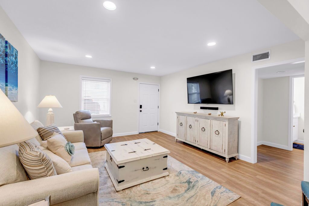 A modern living room with a sofa, armchair, and a television on the wall.