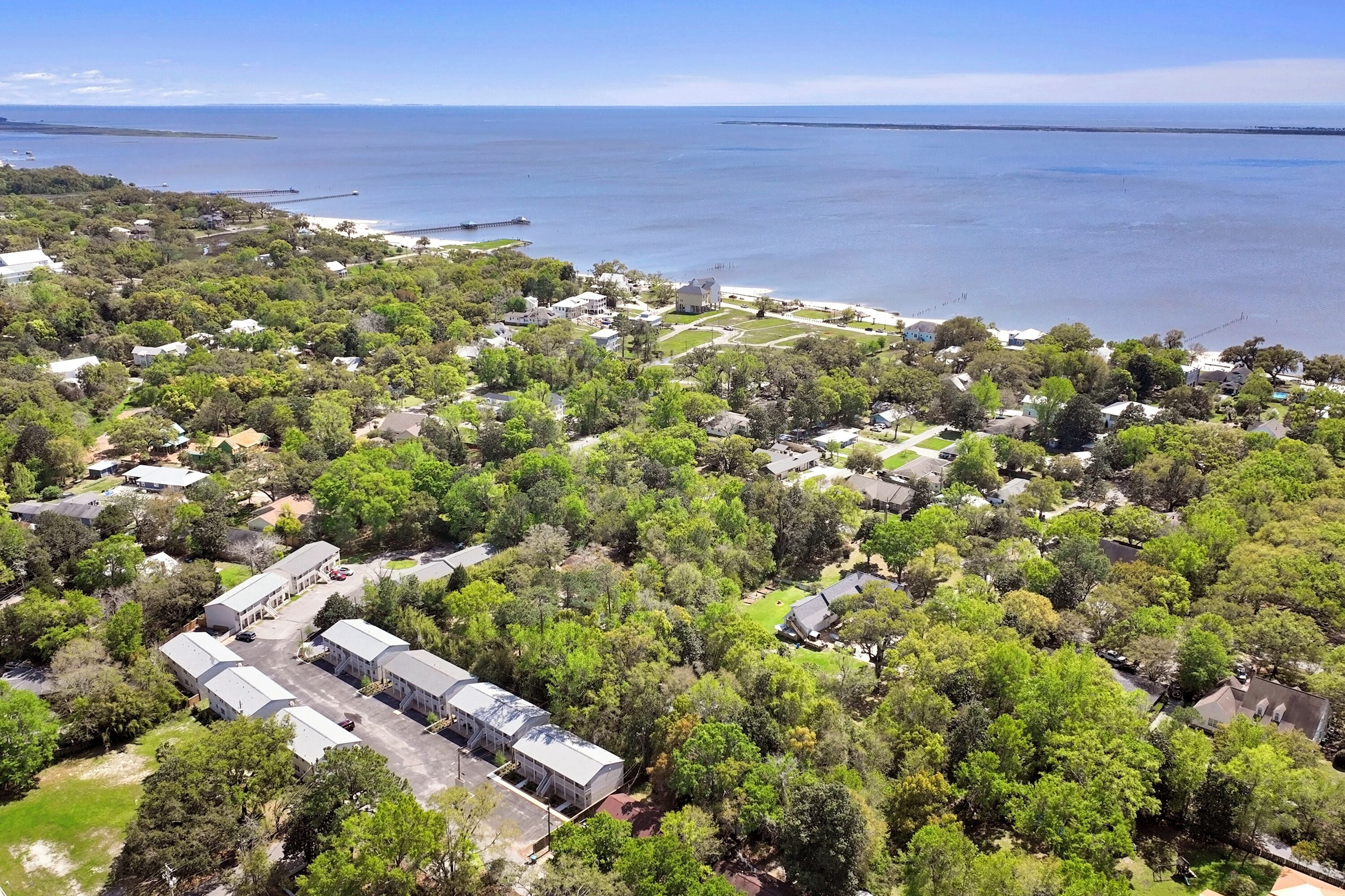 Vista aérea de una zona residencial con casas, espacios verdes y una playa.