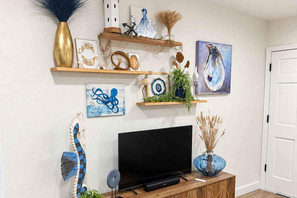 A modern living room with a wooden entertainment unit, a flat-screen TV, and various decorative items including artwork and plants.