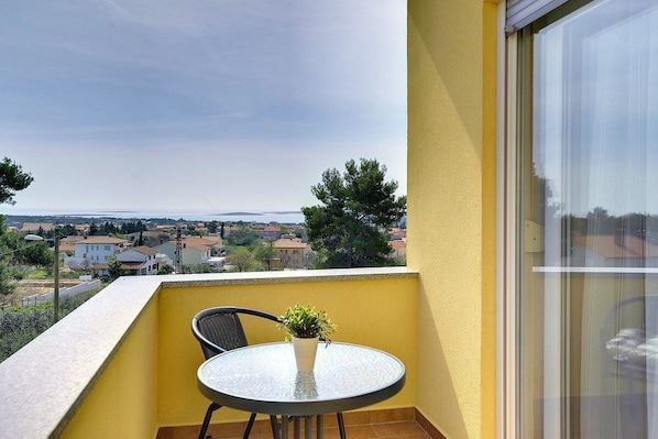 Ein Balkon mit rundem Tisch, einem Stuhl und einem Blumentopf.