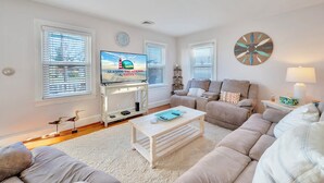 Un soggiorno moderno con televisione, divani, un tavolino e oggetti decorativi.