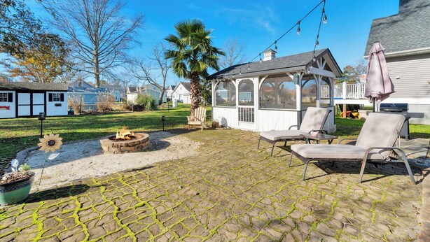 Un patio con un braciere, mobili da esterno e una zona salotto coperta.