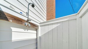 Un recinto in legno bianco con una telecamera di sicurezza in metallo fissata a un muro rivestito di bianco.