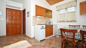 Une cuisine de taille réduite, avec des meubles en bois, une cuisinière blanche et une table à manger avec des chaises.