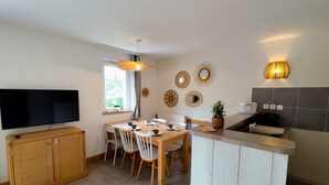 Una cocina moderna con comedor, que incluye un televisor, armarios de madera, una mesa de comedor con sillas y decoración en la pared.