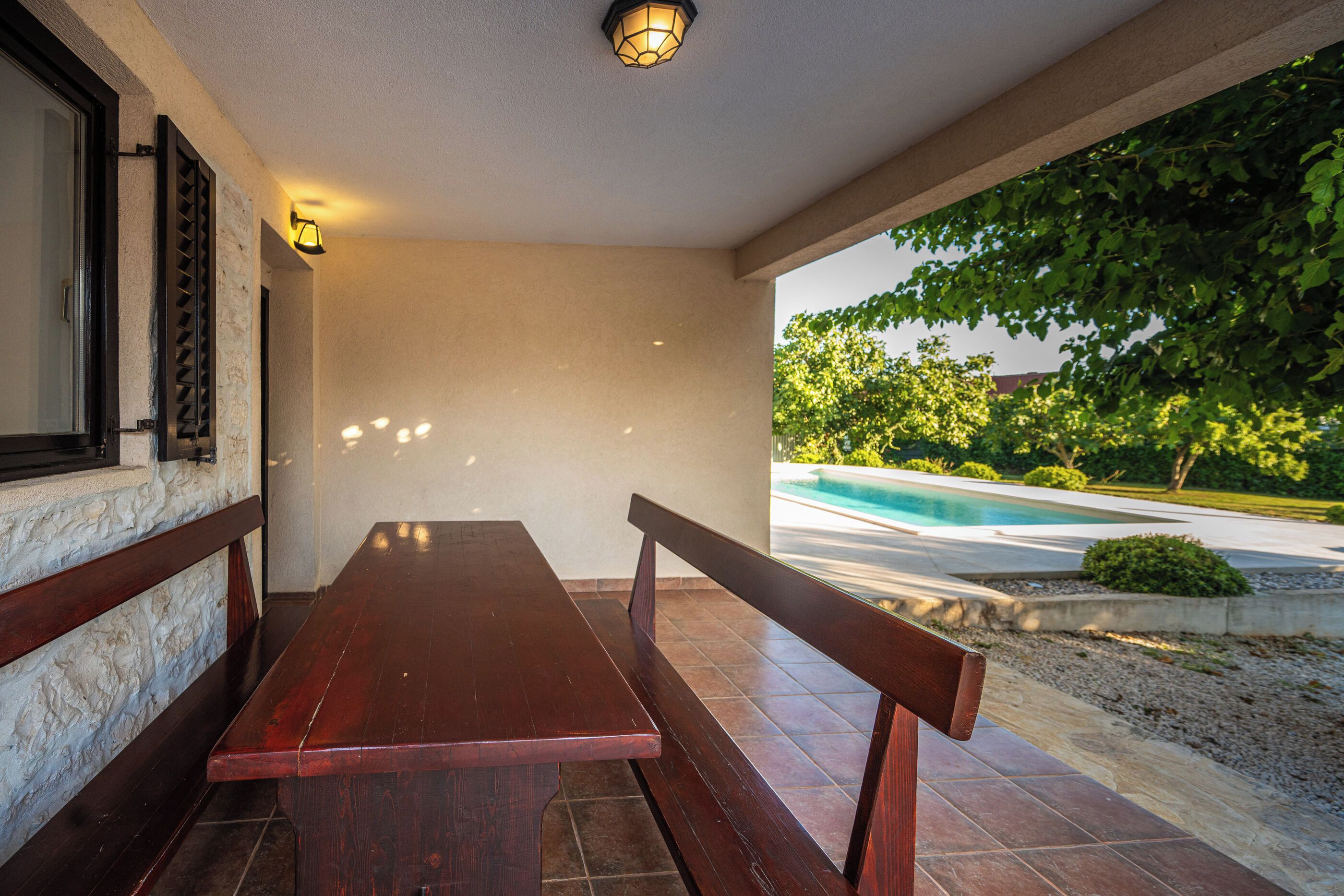 A wooden bench and table set against a wall with a pool view.