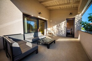 A sunlit patio with a sofa and a table, a door leading to a bedroom, and a wall with a window. - House Fasana (73836-K1) - Fazana (Fazana)