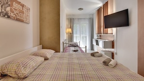 Una habitación de hotel con una cama, televisión, ventana con cortinas y un cartel en la pared.