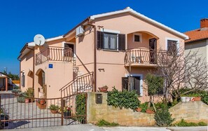 A two-story building with a balcony on the second floor, a satellite dish on the roof, and a gated entrance. - Apartments Bardak (73851-A3) - Liznjan (Liznjan)