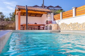 A swimming pool with a wooden deck and stone wall, a barbecue area, and a stone structure. - Apartments Bardak (73851-A3) - Liznjan (Liznjan)