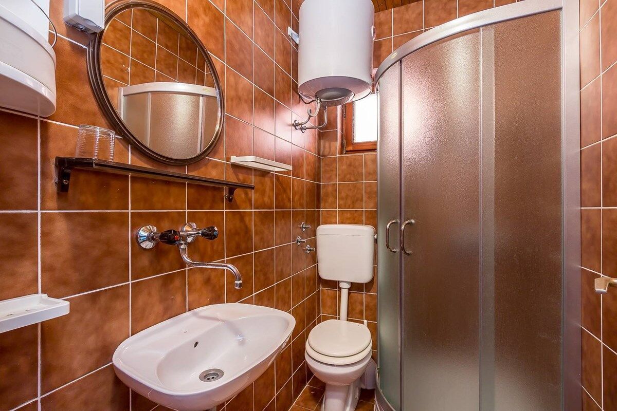 Et badeværelse med vask, toilet, spejl og brusekabine.