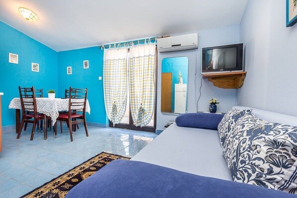 A compact room with a bed, a TV mounted on the wall, a dining table with chairs, and a window with curtains. - Apartments Bardak (73851-A3) - Liznjan (Liznjan)