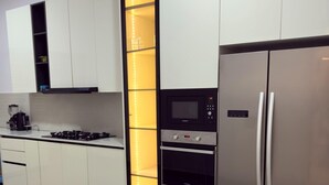 A modern kitchen with white cabinets, a built-in oven, a microwave, and a stainless steel refrigerator. - 4 Bedroom En-Suite, Wi-Fi, Secured, 24/7 Power (Lekki)