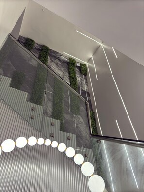 Um interior moderno com piso espelhado, jardins verticais verdes e uma série de luminárias circulares.