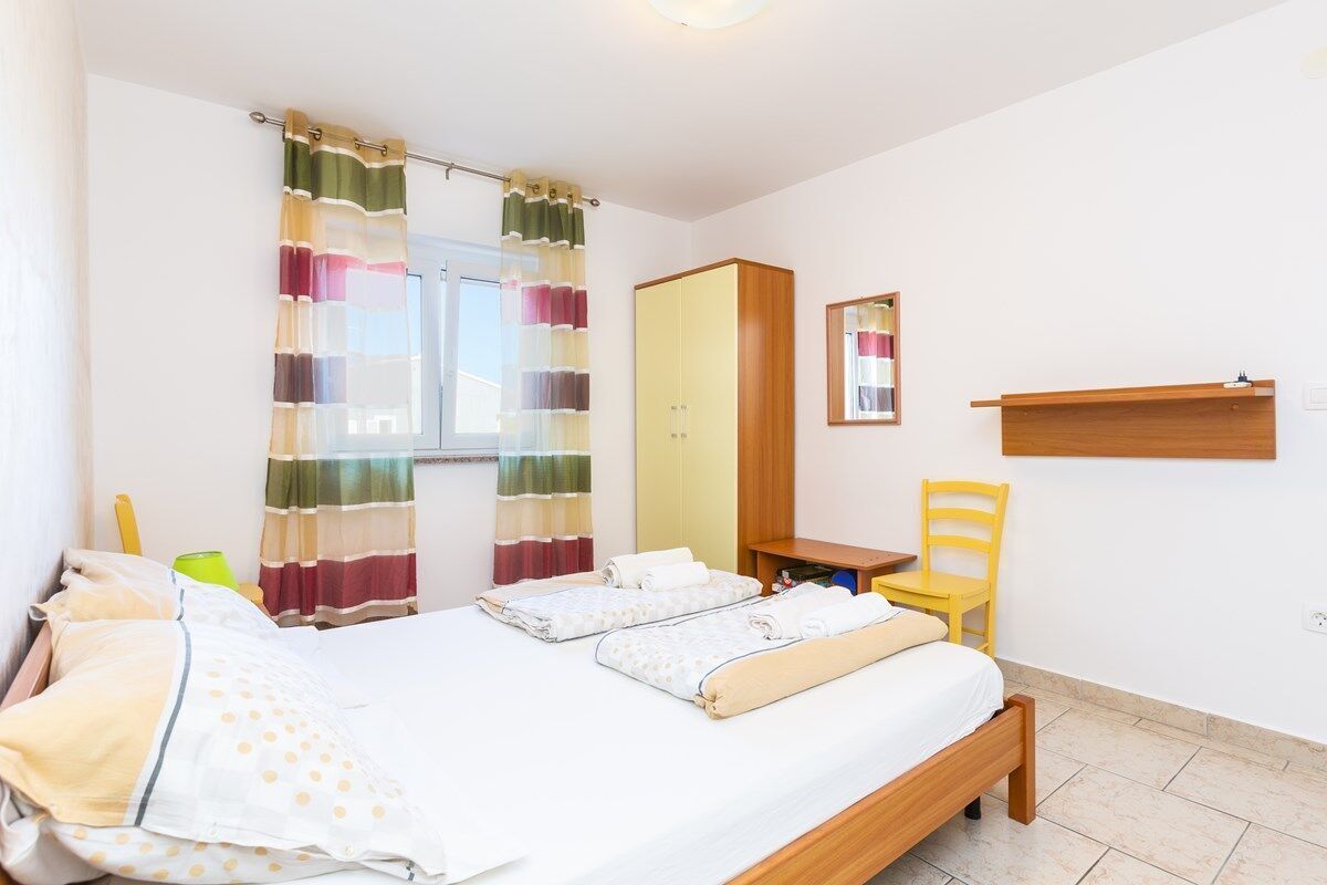 Une chambre à coucher avec un lit, un miroir, une chaise et un bureau.