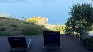 Une terrasse avec deux fauteuils confortables donnant sur une vue panoramique de la côte.