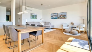 Un salon moderne avec une table à manger en bois, des canapés gris et une grande fenêtre.