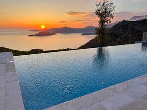 A swimming pool with a sunset view, a tree, and a rocky landscape. - Seaview Hideaway- Premium Apartment (Sveti Stefan)