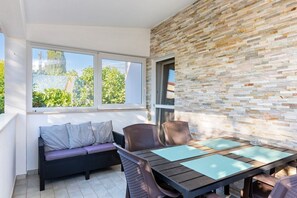 A balcony with a wicker sofa, a wooden table with chairs, and a stone wall. - Apartments Murenc (73888-A2) - Medulin (Medulin)