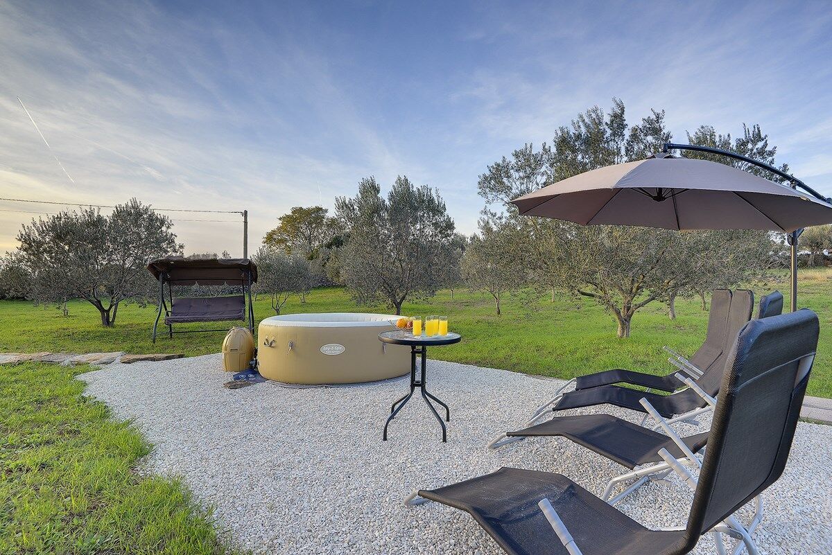 Een terras met lounge stoelen, een jacuzzi en een tafel met drankjes.