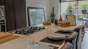 Een moderne keuken met een centraal eiland, donkerhouten kasten, roestvrijstalen apparatuur en hanglampen.