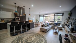 Een moderne keuken met een centraal eiland, barkrukken en hanglampen.