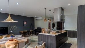 Een moderne keuken met een centraal eiland, donkere kastjes en hanglampen.