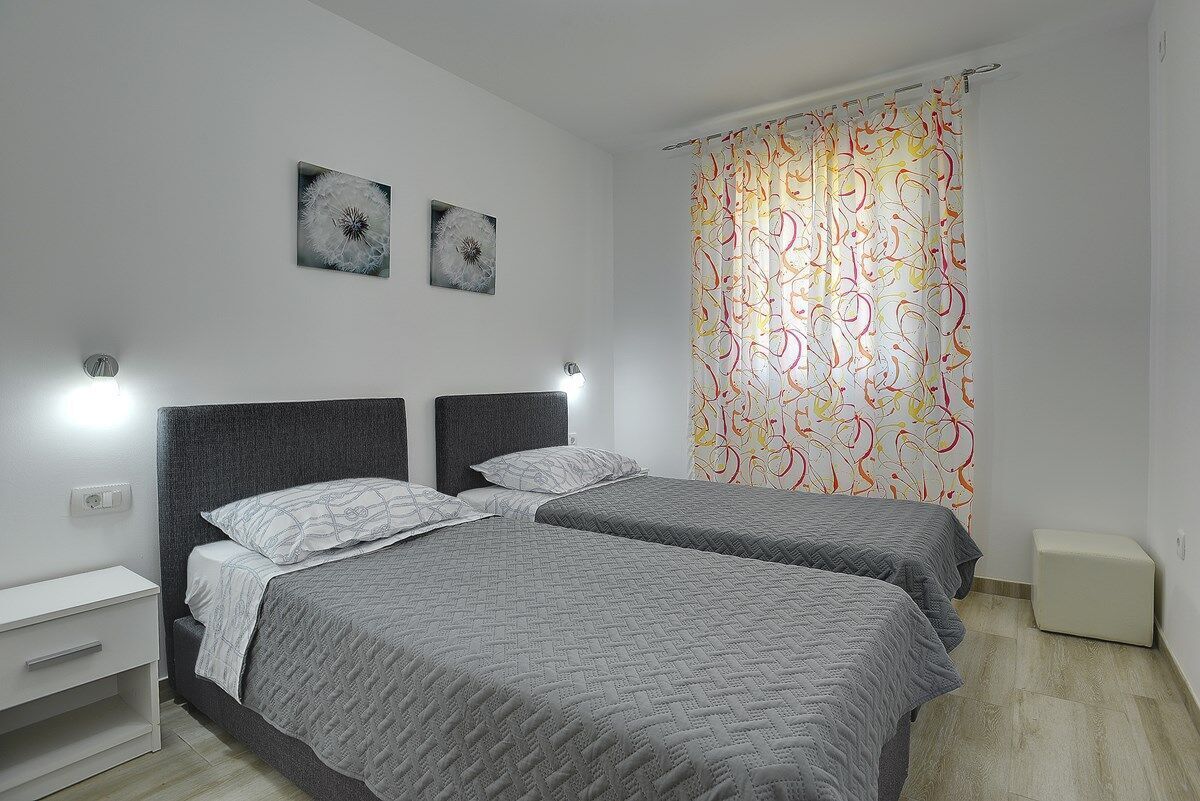 Une chambre avec deux lits, une table de chevet et une lampe fixée au mur.
