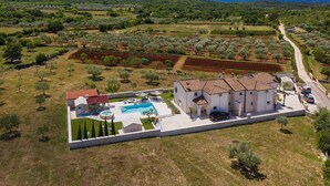 Vista aerea di una proprietà con piscina, una casa grande e uliveti circostanti.