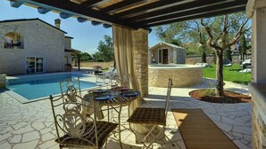 Patio esterno con piscina, pareti in pietra e un pergolato.